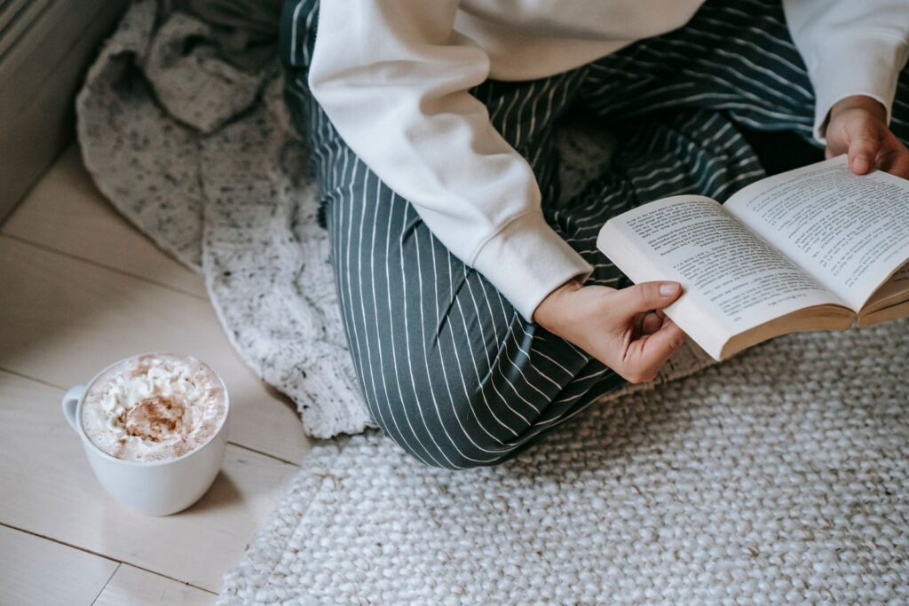 Mujer leyendo un libro mientras toma un cafe, disfrutando de tiempo libre