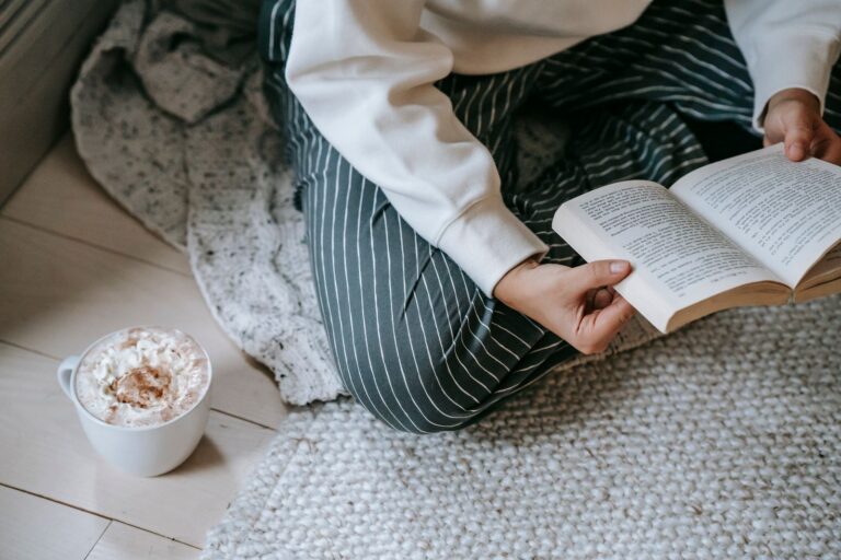 Mujer leyendo un libro mientras toma un cafe, disfrutando de tiempo libre