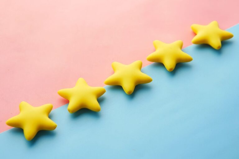 Estrellas amarillas de calificacion sobre fondo rosado y azul pastel, representando resenas en linea