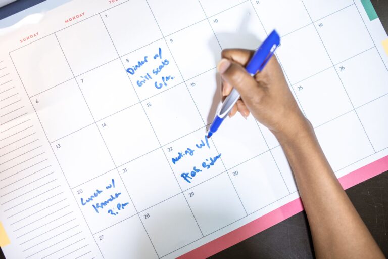 Persona escribiendo citas en un calendario con un boligrafo azul
