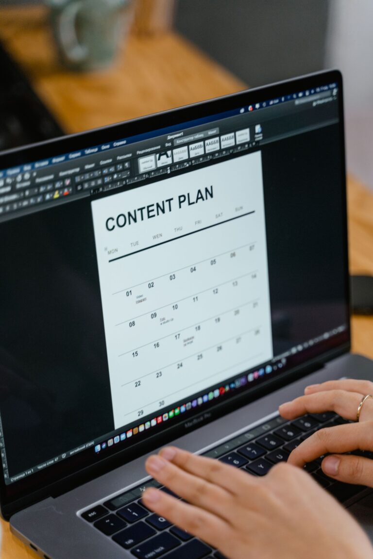 Manos escribiendo en un laptop con un plan de contenido en pantalla